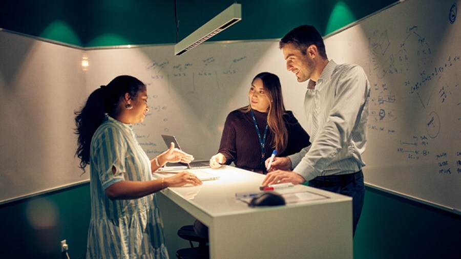 Team collaborating at a whiteboard table in a modern office setting.