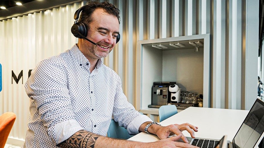 Customs services employee sitting at a desk with a laptop open, wearing a headset