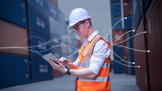 Worker using tablet among shipping containers