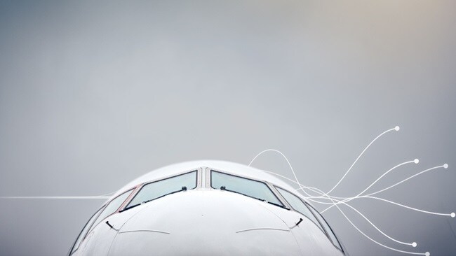 A commercial airplane soaring through the sky with a single cloud in the background.