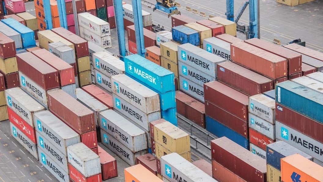 Aerial view of a large container yard filled with colorful shipping containers arranged in neat rows.