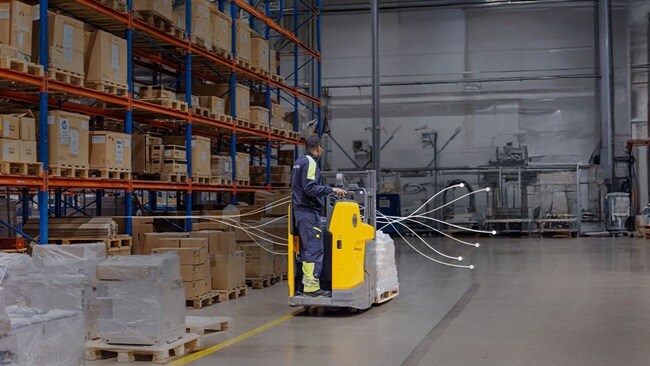 Warehouse worker operating a yellow pallet mover
