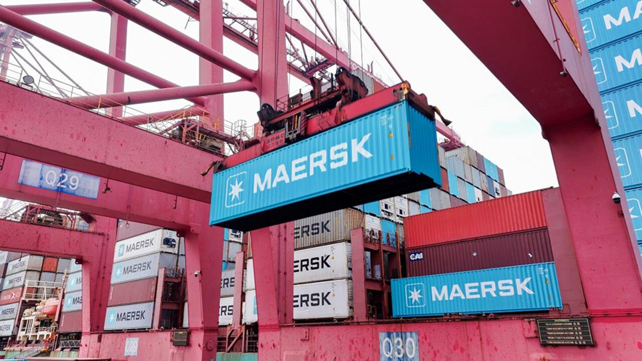 Blue Maersk container being moved by a crane in a terminal.