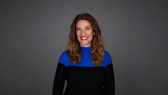 Portrait of a person in a blue and black top against a grey background.