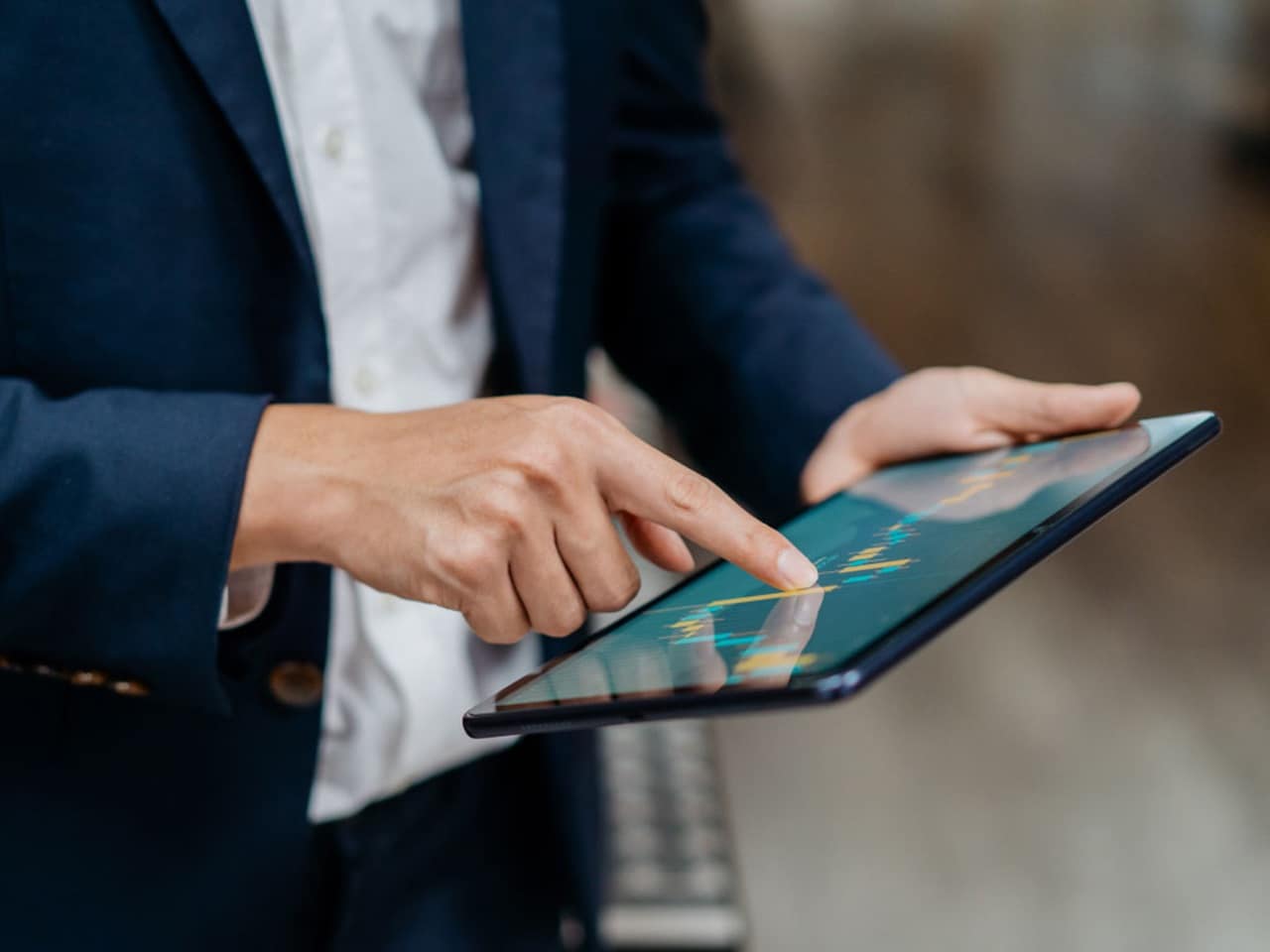 A person in business attire uses a digital tablet.