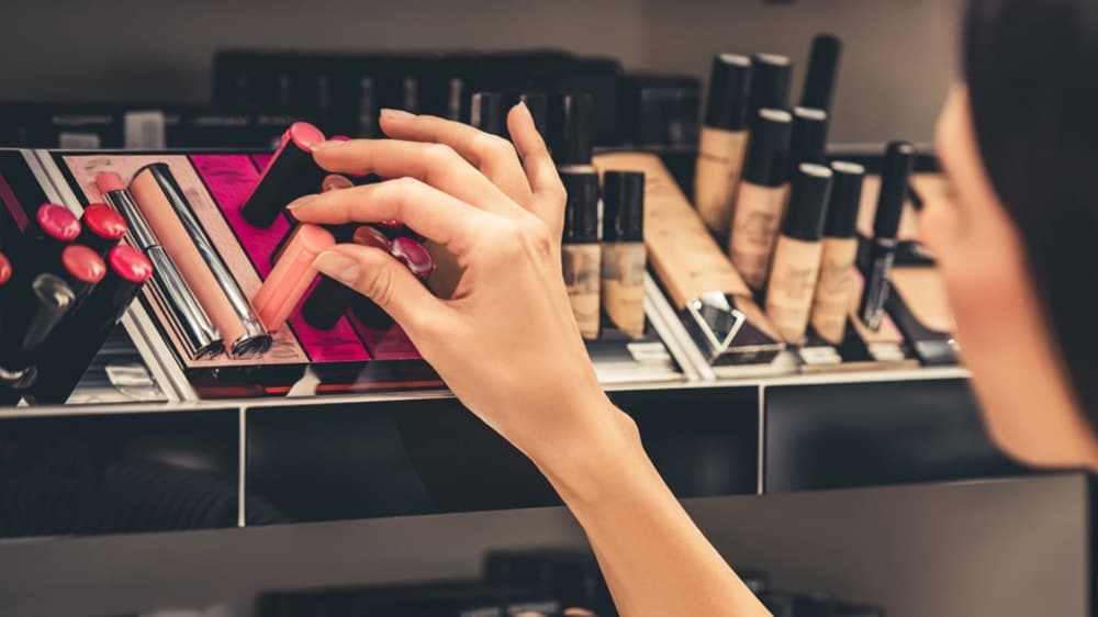 顧客從化妝品商店的展示櫃中挑選唇膏。