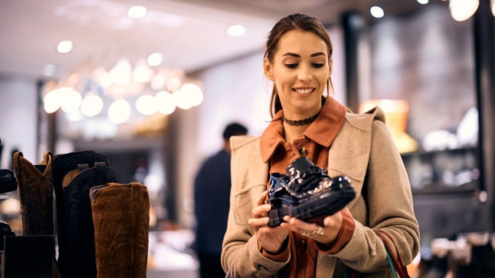 A woman examines various shoes displayed in a retail store.