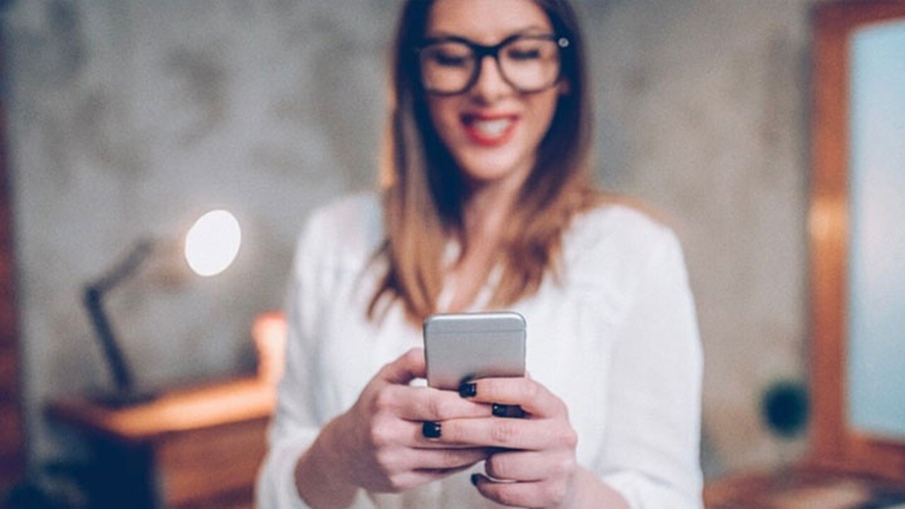 面向 D2C 營銷的物流 - 一位快樂的年輕女士在查看她的行動電話。