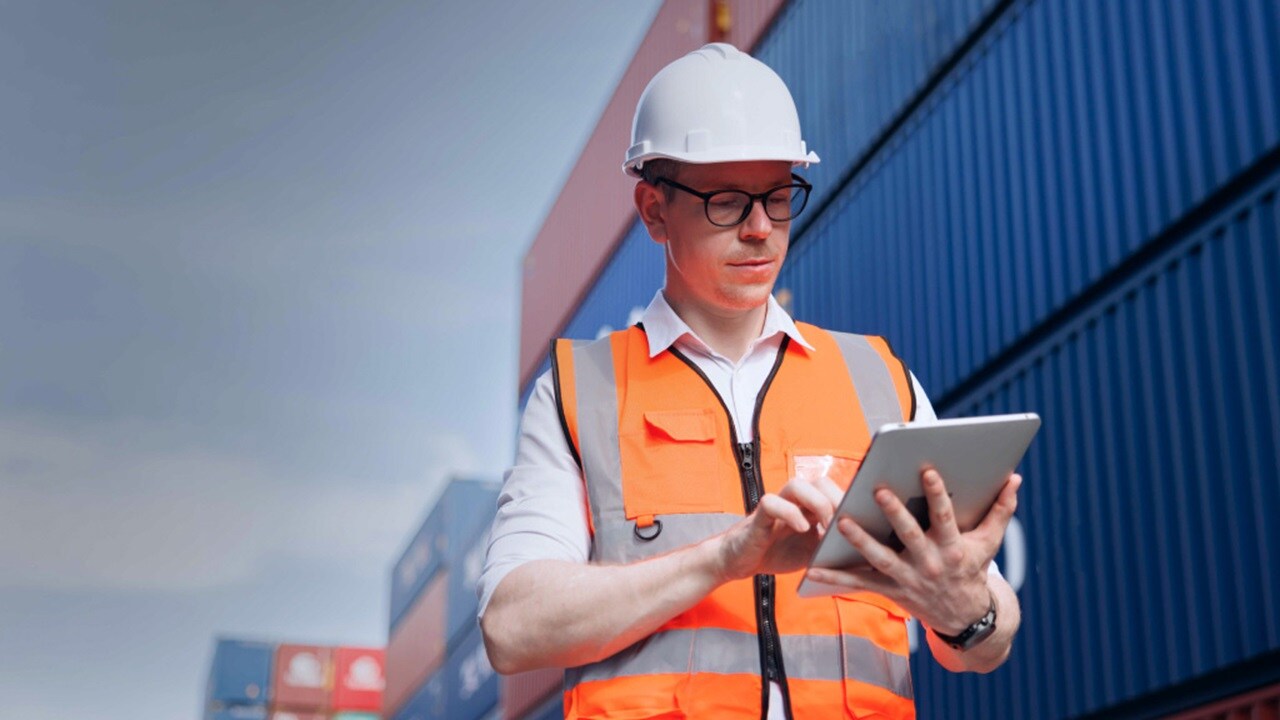 Logistics professional using a digital device at a port site
