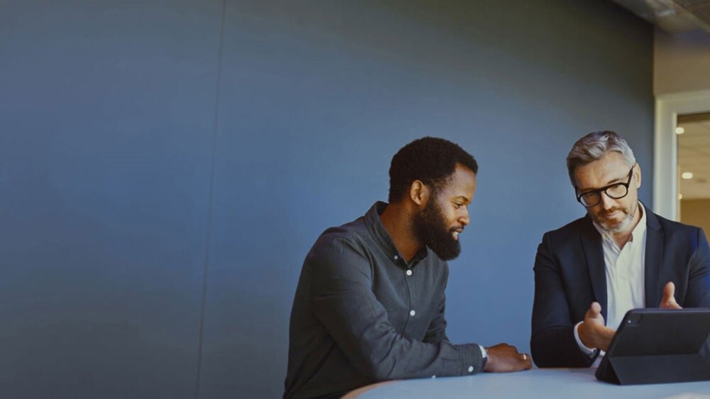 Two businessmen are discussing the ECTN essentials using a digital tablet.