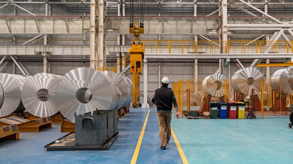 Two businesspeople in suits shake hands, with a third person in the background, symbolizing agreement or partnership.